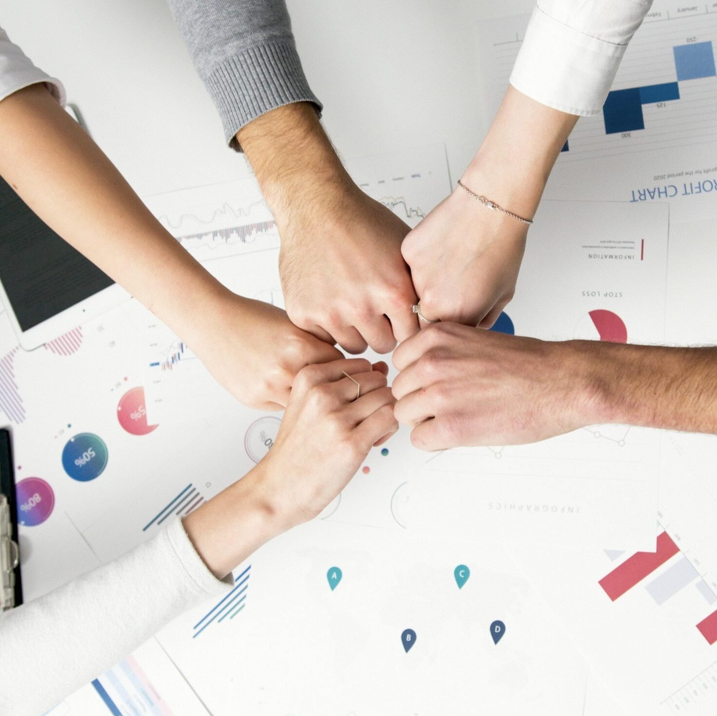 Colleagues celebrate success with a fist bump over financial charts depicting teamwork and unity.